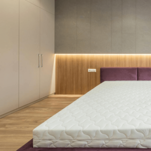 Modern bedroom with hidden storage space, featuring sleek built-in wardrobes, a wooden accent wall with integrated lighting, and a minimalist bed with a white mattress.