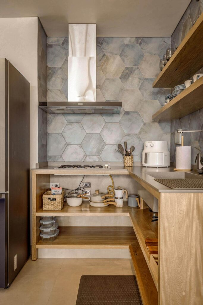 Modern tiny kitchen with open wooden shelves, hexagonal tile backsplash, compact gas cooktop, and organized storage for cookware and dishes. A great example of maximizing functionality in a small kitchen space.