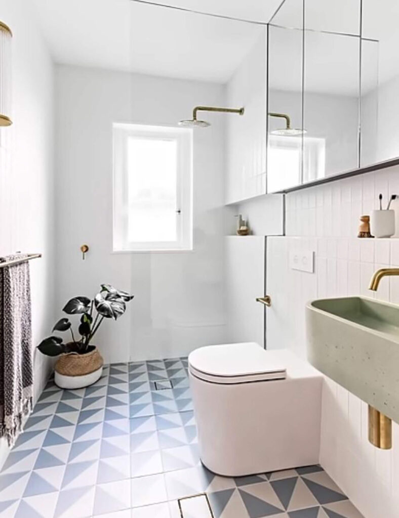 Bright small bathroom with geometric patterned floor tiles, mirrored cabinets, and green basin, providing ample storage and modern style.