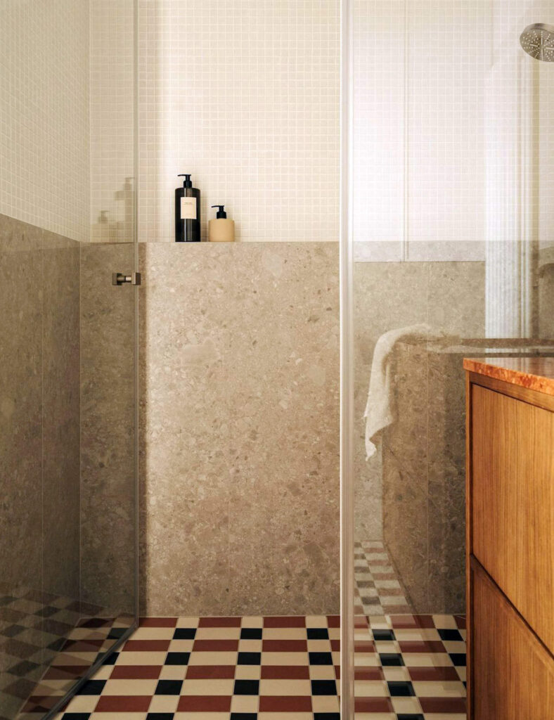 Neutral-toned shower with a small built-in niche in the tiled wall, storing black and beige soap dispensers.