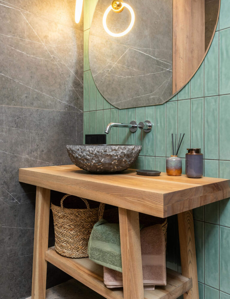 A bathroom with a wooden vanity and stone basin, showcasing under-sink storage with woven baskets and neatly folded towels on an open shelf.