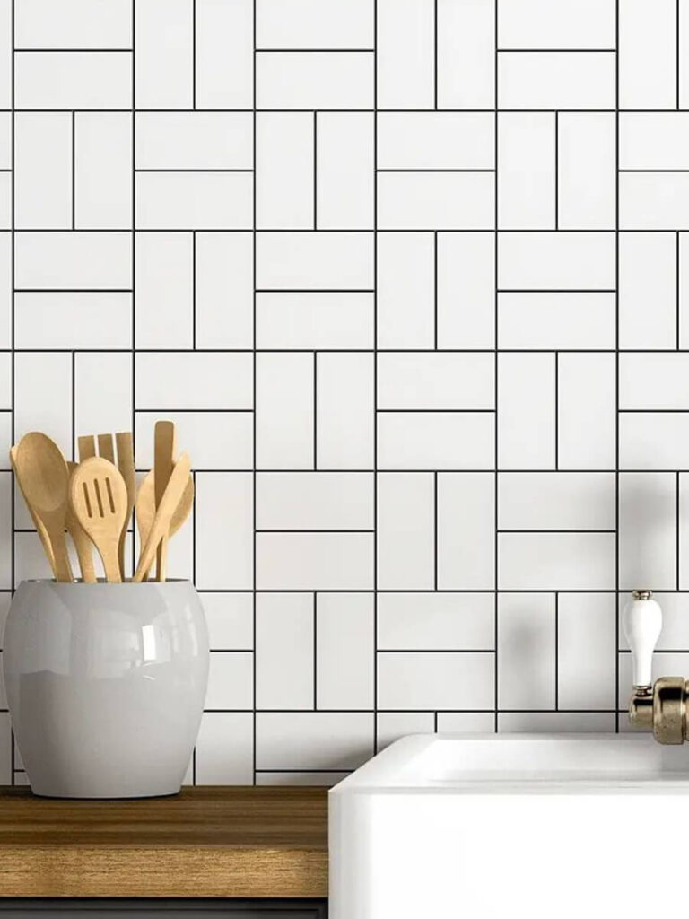 Kitchen backsplash featuring glossy white basket weave tiles, arranged with black grout, wood countertop, and modern accessories for a streamlined, graphic effect.