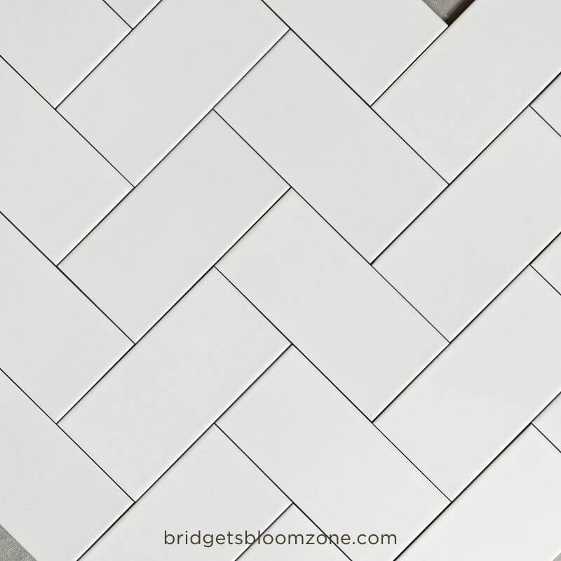 White rectangular subway tiles laid out on the floor in different patterns to test layout ideas for a small white bathroom.