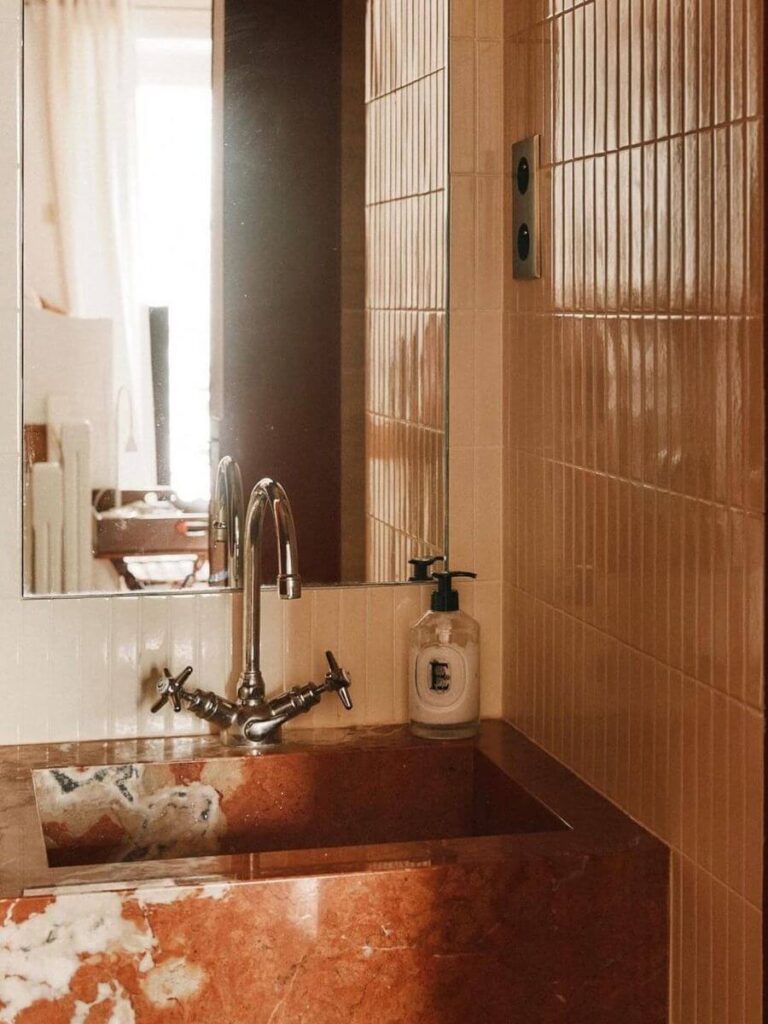 Natural wood and beige walls with terracotta tile floor, featuring a round stone sink for grounded small bathroom color ideas and earthy Bathroom Color Schemes.