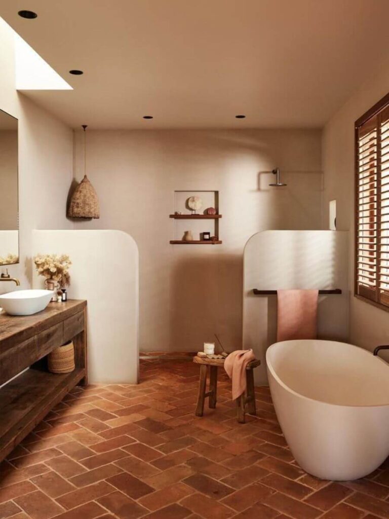 Spacious beige and terracotta bathroom with freestanding tub, wood accents, and herringbone tile floor, perfect for cozy small bathroom color ideas.