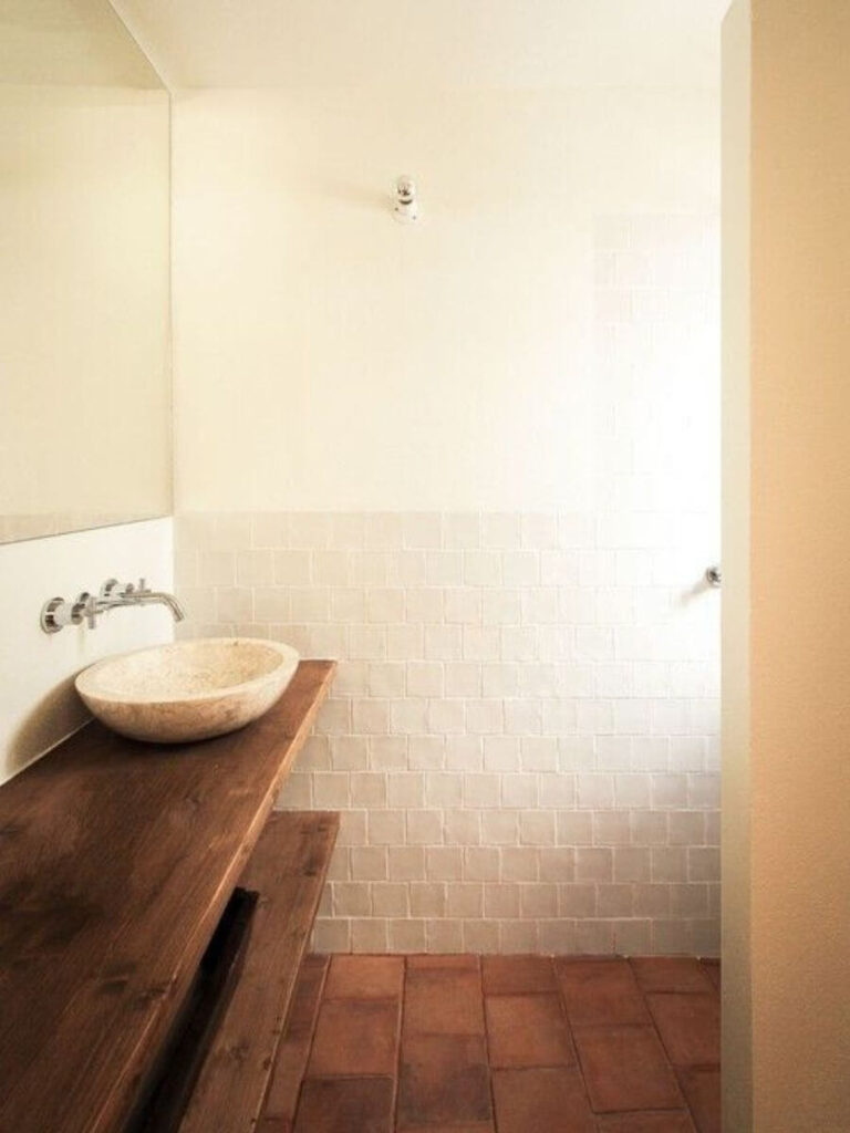 Warm-toned sink with beige tile wall and gold fixtures in soft afternoon light gives cozy small bathroom color ideas with vintage inspiration.