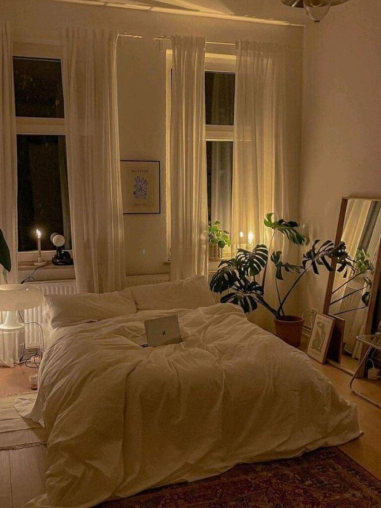 A small bedroom photographed in early evening. Small bedside lamps providing layered bedside lighting in a small bedroom — overhead light off