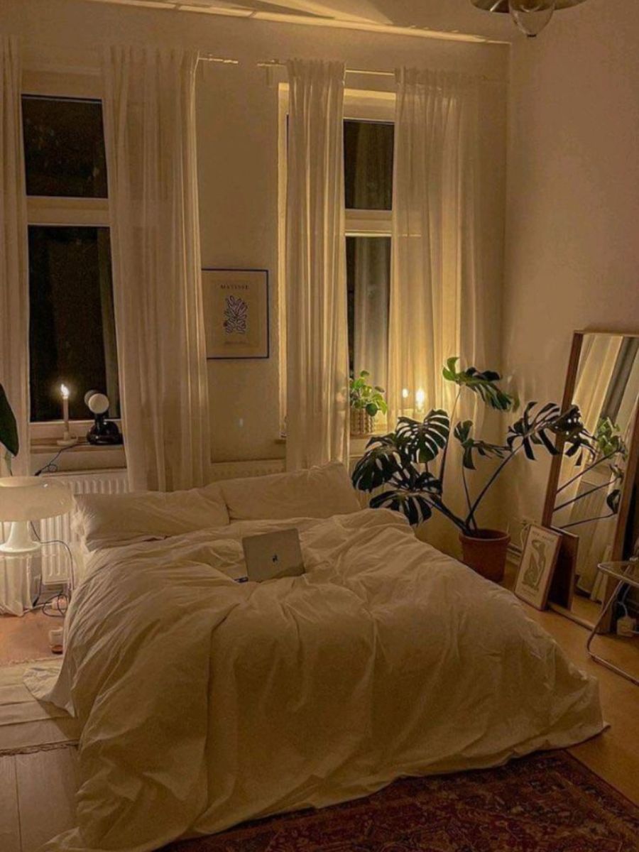 A small bedroom photographed in early evening. Small bedside lamps providing layered bedside lighting in a small bedroom — overhead light off