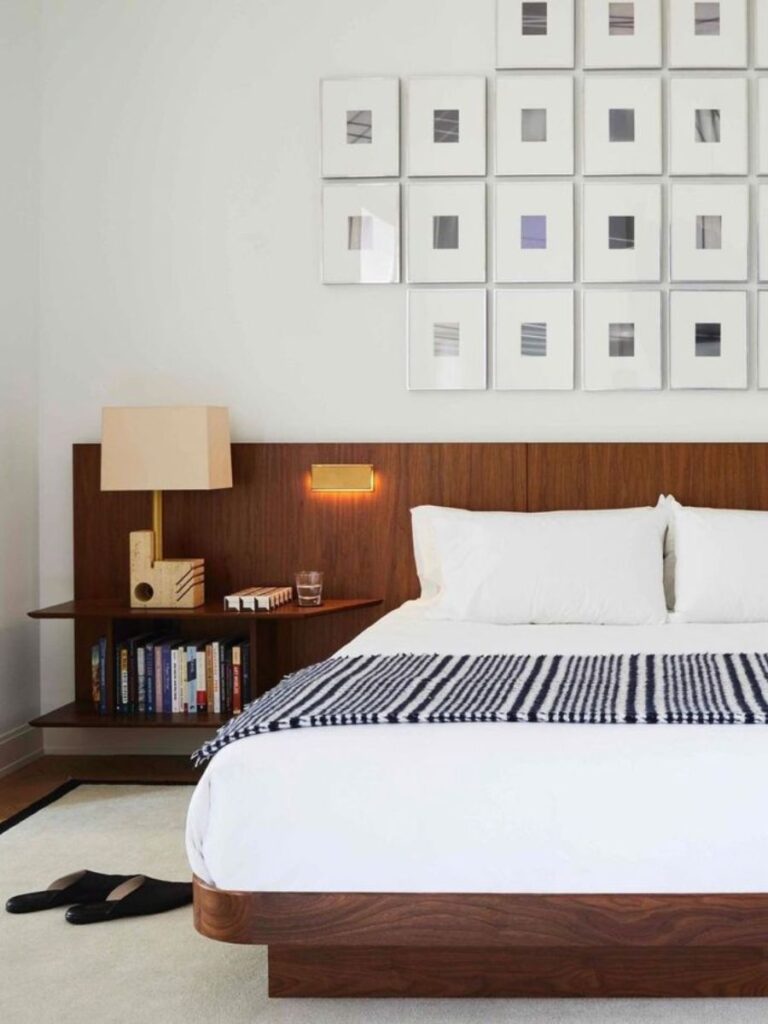 Minimalist bedroom with a bed, its wooden headboard continues behind the floating wooden nightstands. The size of the nightstands is chosen to be big enough to hold items.